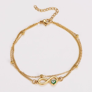Detail of double-layer gold anklet with infinity symbol and green evil eye bead charm