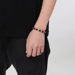 Detail of men's braided leather bracelet with textured metal beads and black beads