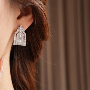 Close-up of geometric zircon earrings with a large rectangular stone on a model ear