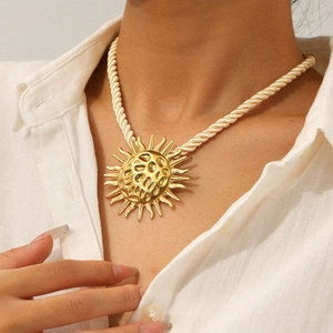 Bohemian gold sun pendant necklace with hammered texture on a cream braided rope cord