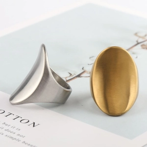 Macro view of minimalist silver conical and gold oval stainless steel rings on a magazine
