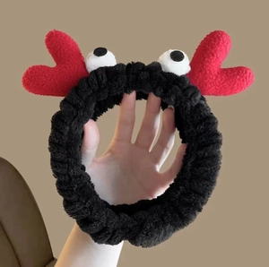 Close-up of black plush crab-style headband with red hearts and cute cartoon eyes