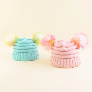 Close-up of knit texture and colorful gradient faux fur pom-poms on children's winter beanies