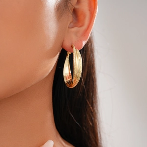 Detail of 18k gold plated triple layered hoop earrings on model showing textured finish