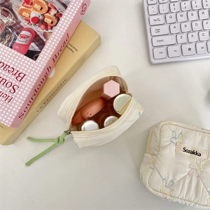 Detailed view of quilted cotton pouches showing embroidery and soft padded texture