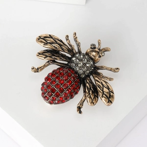 Detailed view of vintage bronze bee brooch with red rhinestones and intricate wings