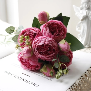 Top view of deep pink artificial peonies with layered petals on lace cloth