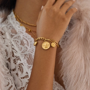 Vue détaillée du bracelet à breloques en acier doré 18K avec pièce d'ange sur le poignet