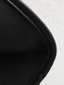 Close-up of black faux leather texture and reinforced edge stitching on winter coat
