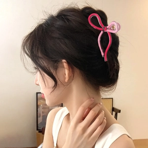 Pink jelly bow hair claw clip shown on hair from a side view for women's hairstyle
