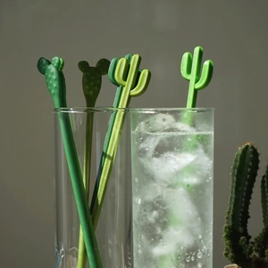 Set of four green cactus and bear shaped plastic stirrers in a glass of ice water