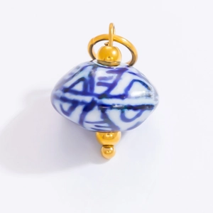 Detailed close-up of blue and white porcelain oval pendant with gold metal findings