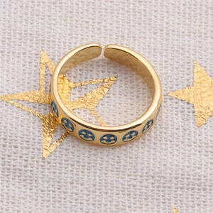 Detail of a gold plated adjustable ring featuring blue enamel smiley face patterns