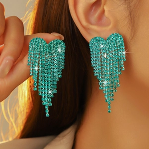 Close-up of heart-shaped blue rhinestone tassel earrings worn on a model ear
