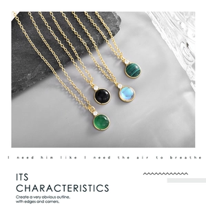 Detail of round gemstone necklaces in multiple colors on grey stones with gold plating