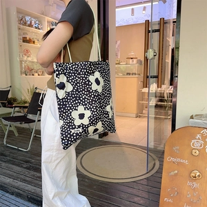 Grand sac fourre-tout en toile à motifs floraux blancs porté lors d'une séance lifestyle