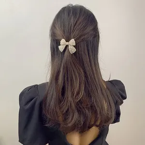 Detailed back view of an elegant cream pearl bow hair clip on wavy brown hair