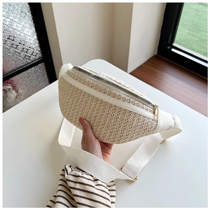 Detailed close-up of a beige straw woven fanny pack with a white strap and gold zipper