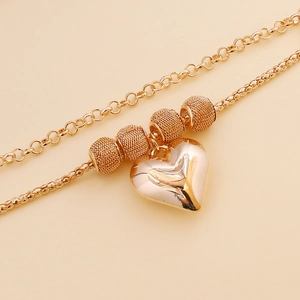 Close-up of gold layered heart necklace with textured beads and mixed chain styles