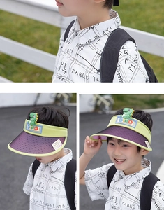 Detailed view of kids' green sun visor with cute 3D dinosaur and purple tinted shield