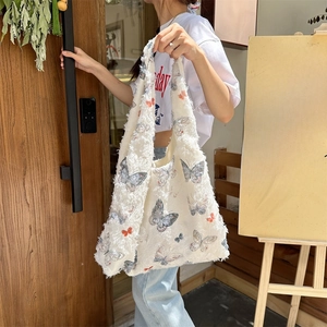 Lace butterfly print canvas hobo bag with fringe details shown in outdoor lifestyle setting