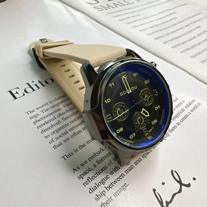 Close-up of a stylish quartz watch with beige silicone strap on an English news background