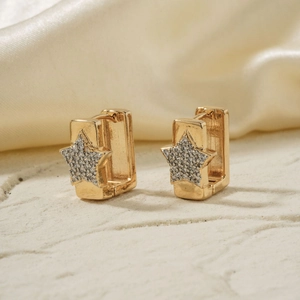 Detailed close-up of gold star earrings with micro-set zircon stones on silk