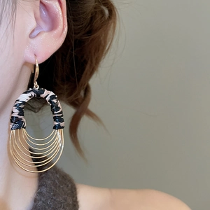 Detail of layered gold oval hoop earrings with leopard print leather on model