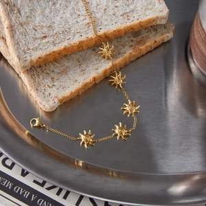 Bracciale di lusso in acciaio al titanio dorato con pendenti a sole su vassoio da colazione