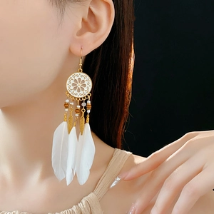 Gros plan de boucles d'oreilles attrape-rêves bohèmes avec plumes et feuilles dorées