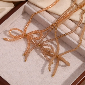 Detailed macro view of champagne beaded necklace with elegant crystal bow accents