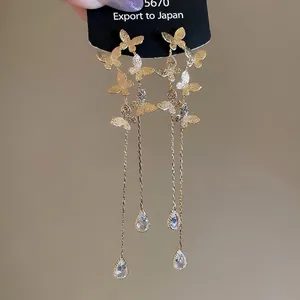 Gold butterfly tassel earrings with long chain and crystal drop displayed on a card