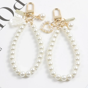 Détail d'un porte-clés perle en cœur avec pendentif coquille dorée et fermoir mousqueton