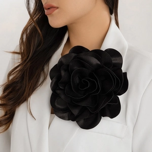 Large black satin rose brooch pinned on a white blazer, elegant floral suit accessory