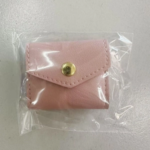 Pink faux leather jewelry pouch detail showing gold snap closure in clear plastic packaging