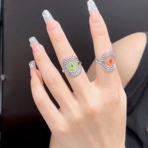 Close-up of vintage flower rings with green and orange accents on model hands
