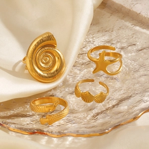 Gold starfish and seashell 4-piece ring set in a textured glass dish on satin background