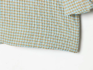 Makro-Detail des blau-braunen Seersucker-Karostoffs mit feiner Textur und Nähten