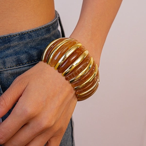 Macro detail of elastic chunky bracelet with gold metal bars and amber resin blocks
