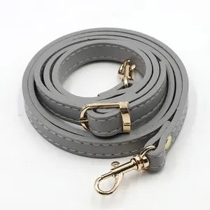 Detail of grey PU leather bag strap with golden metal buckle and white stitching