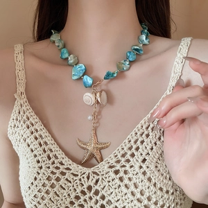 Detail of bohemian necklace with turquoise stones, gold starfish, and natural shells
