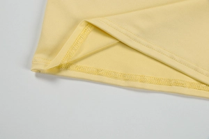 Detail of light yellow dress hem showing high-quality double-needle stitching and fabric