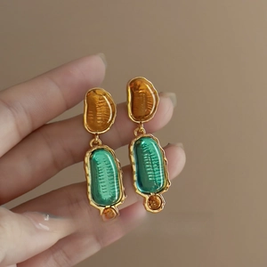 Detail of vintage irregular resin earrings featuring amber and green geometric pendants