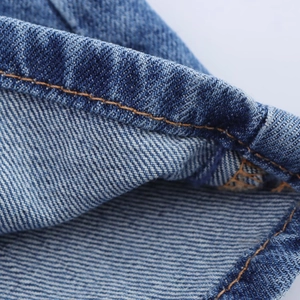 Κοντινή λήψη μπλε υφάσματος denim που δείχνει την υφή twill και τις λεπτομερείς ραφές