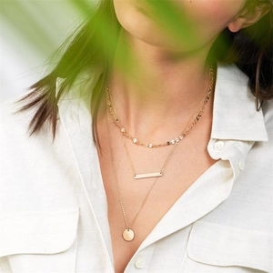 Gold-layered stainless steel necklace featuring geometric pendants on a model