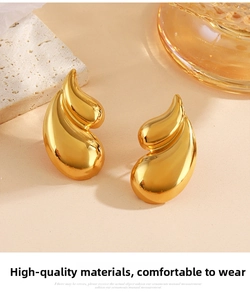 Macro shot of gold teardrop earrings with high-polish finish on natural stone background