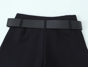 Detailed view of black trousers waist with a matching wide faux leather belt texture
