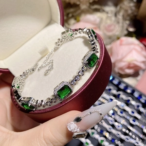 Close-up of vintage emerald gemstone bracelet with pavé diamonds in a red jewelry box