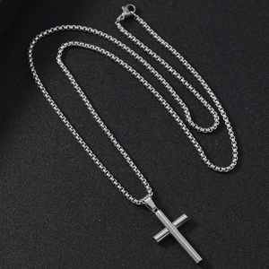 Polished silver stainless steel cross pendant necklace with box chain for men on dark fabric