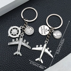 Close-up of silver airplane and globe keychains with 'no matter where' engraving